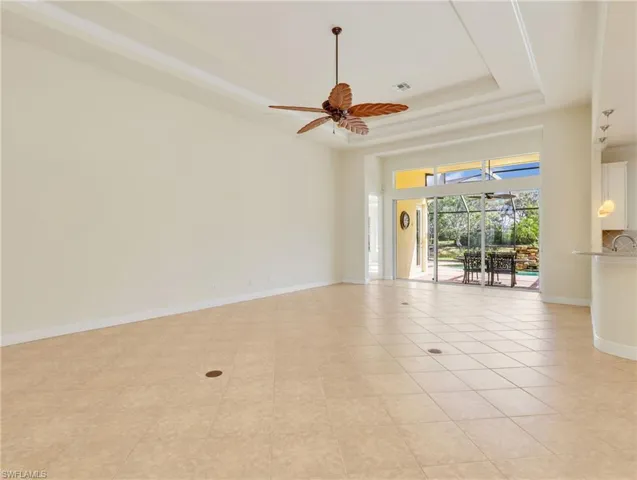 Unfurnished room featuring a ceiling fan, a sunroom, and a raised ceiling