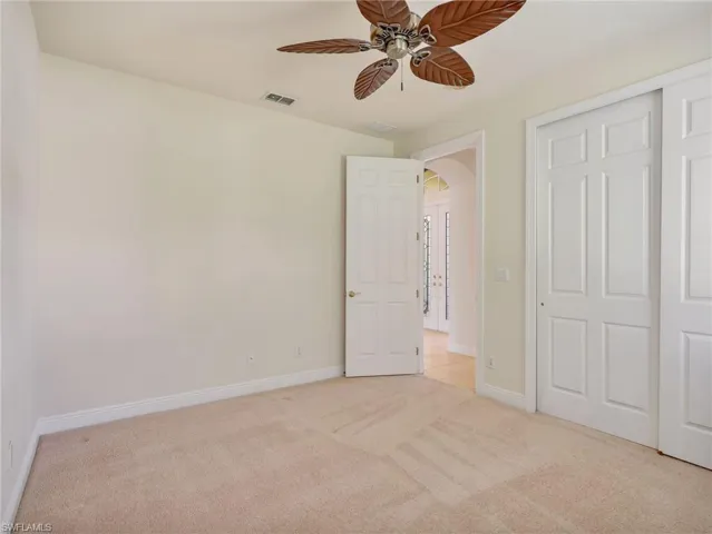 Unfurnished bedroom with light colored carpet, ceiling fan, and a closet