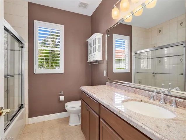 Full bathroom featuring vanity, shower / bath combination with glass door, and light tile patterned floors