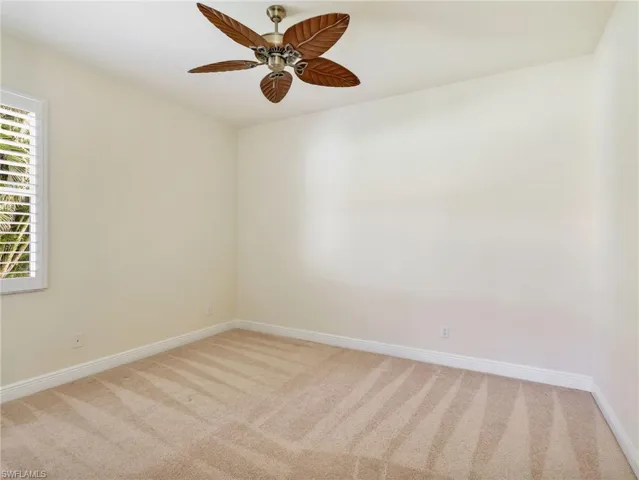 Empty room with light carpet and a ceiling fan