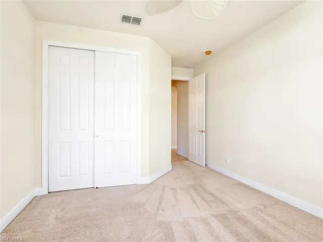 Unfurnished bedroom with light carpet, a ceiling fan, and a closet