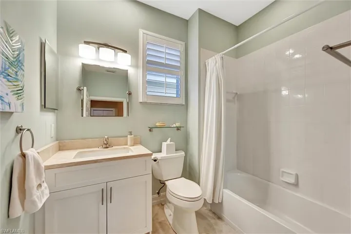 Bathroom with toilet, shower / bath combo with shower curtain, and vanity