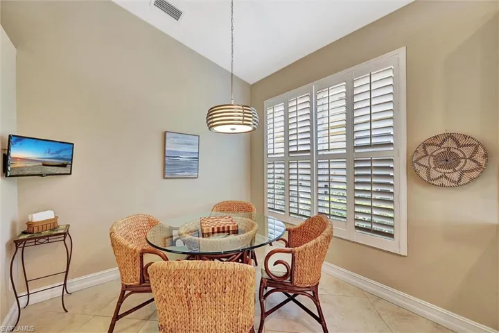 Dining area with tile patterned floors, baseboards, lofted ceiling.