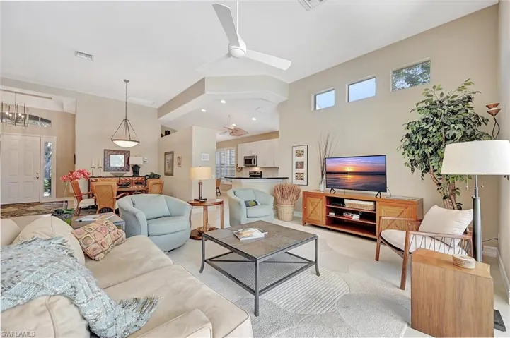 Living room featuring a high ceiling, ceiling fan, and plenty of natural light