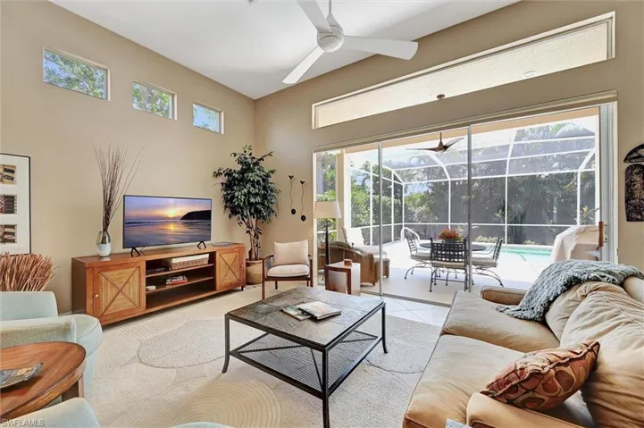 Living room featuring a sunroom, tile patterned flooring, and a ceiling fan