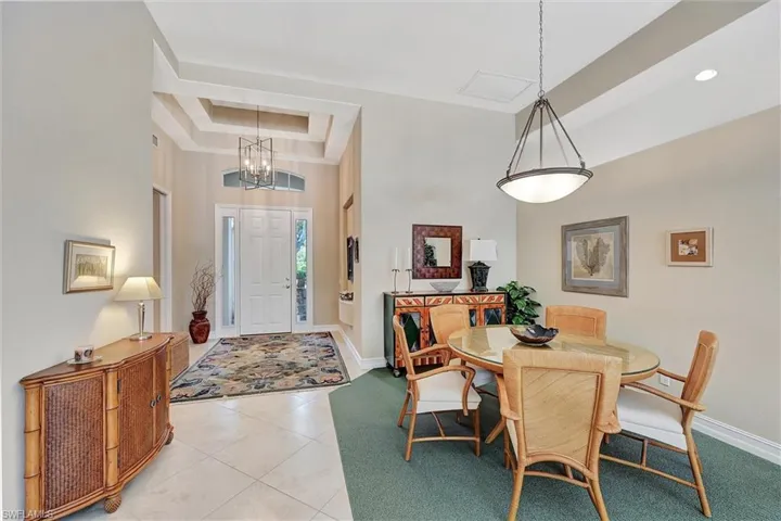 Dining room with a chandelier, baseboards, a raised ceiling, a high ceiling, and light tile patterned floors