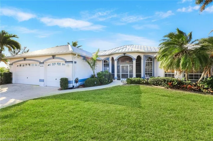 Mediterranean / spanish-style home with stucco siding, a front yard, driveway, a garage, and a standing seam roof