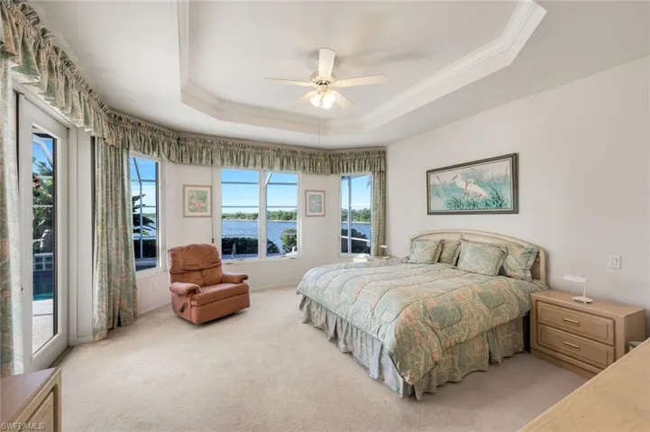 Bedroom with crown molding, access to outside, a ceiling fan, light colored carpet, and a tray ceiling