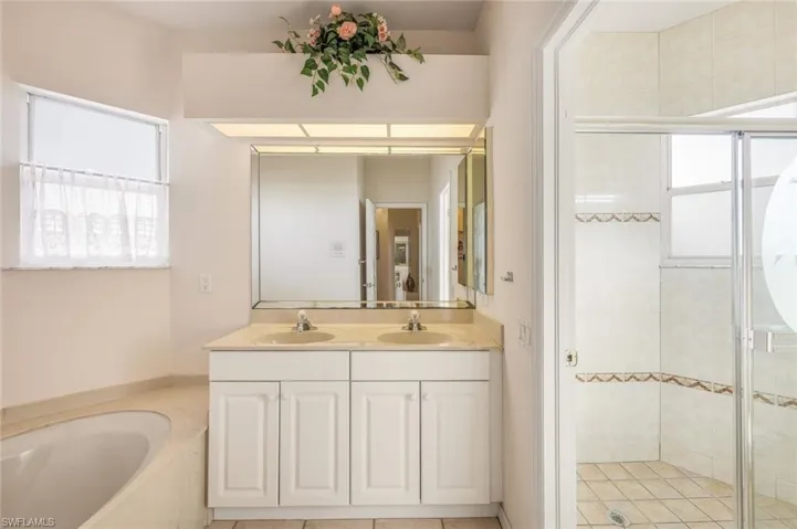 Full bath with double vanity, a stall shower, and a garden tub