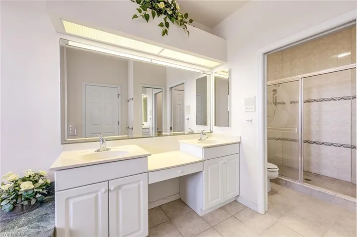 Full bath with a stall shower, double vanity, and light tile patterned flooring