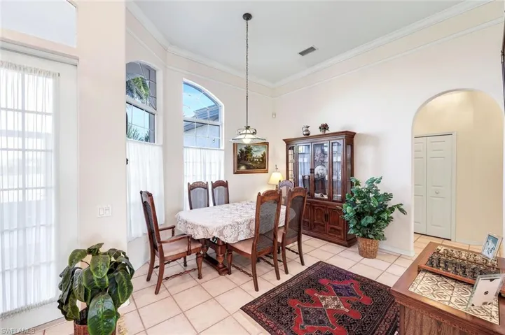 Dining area featuring arched walkways, ornamental molding, light tile patterned flooring, and a high ceiling