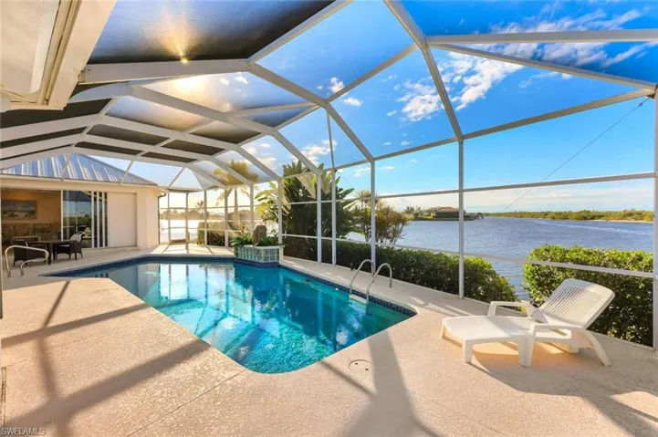 Outdoor pool with a sunroom, glass enclosure, a patio, and a water view