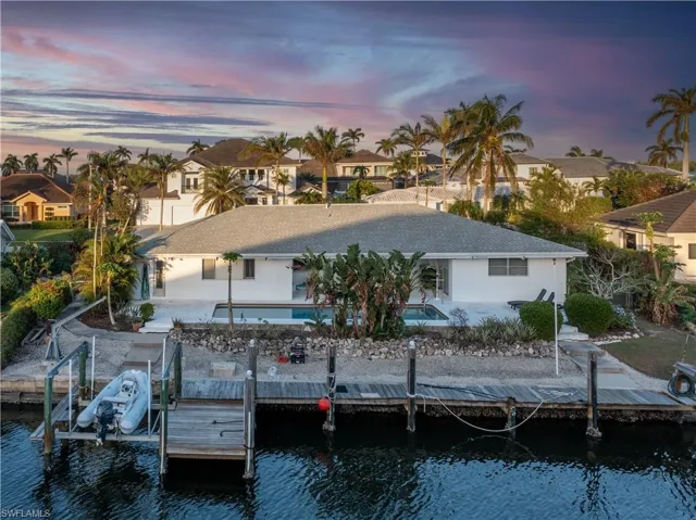 Back house at dusk with a water view and a patio