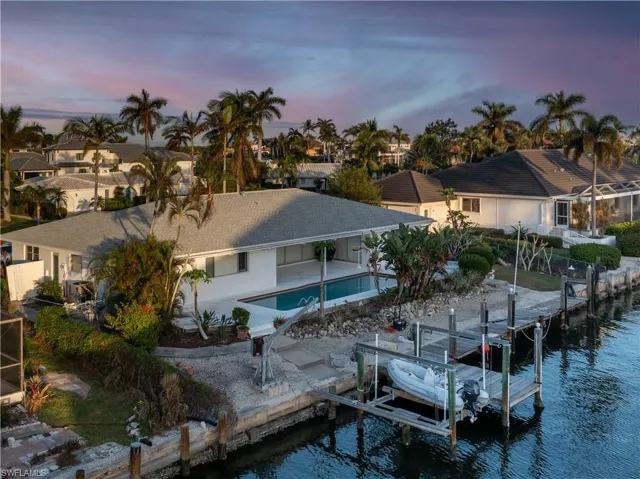 Back house at dusk featuring a water view and a patio area