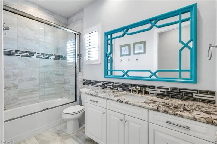 Full bathroom with vanity, enclosed tub / shower combo, and custom backsplash