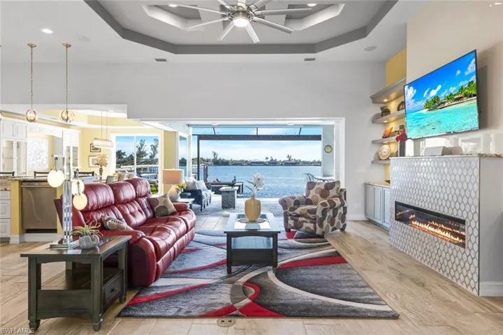 Great Room featuring a coffered ceiling, a tiled fireplace, custom ceiling fan, and custom tile flooring throughout