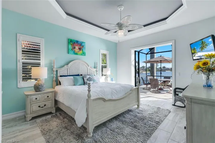 Bedroom with a tray ceiling, access to the lanai, custom ceiling fan and ornamental molding