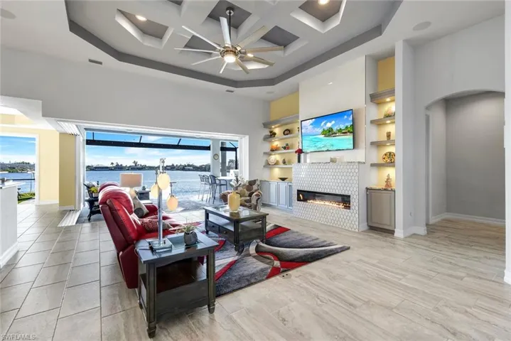 Great Room with coffered ceiling, custom ceiling fan, a tile fireplace, and custom tile flooring throughout