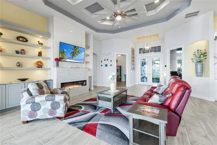 Great Room featuring a coffered ceiling, a custom ceiling fan, french doors, and a tile fireplace
