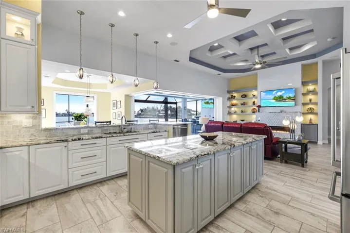 Kitchen with granite countertops, decorative custom light fixtures, coffered ceiling, open floor plan, and gray cabinetry