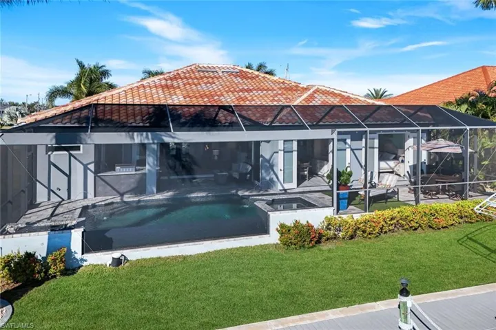 Rear view of property featuring an outdoor pool, screen enclosure and yard