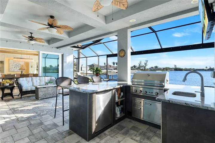 View of lanai, featuring custom ceiling fans, an outdoor kitchen and views of Lavedo Lake