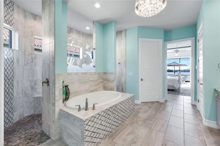 Ensuite bathroom with a garden tub, vanity, walk in shower, recessed lighting, and a chandelier