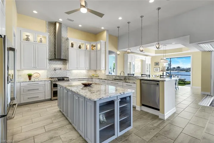 Kitchen featuring wine storage cabinet, gray cabinets, glass insert cabinets, granite counters, island and white cabinetry