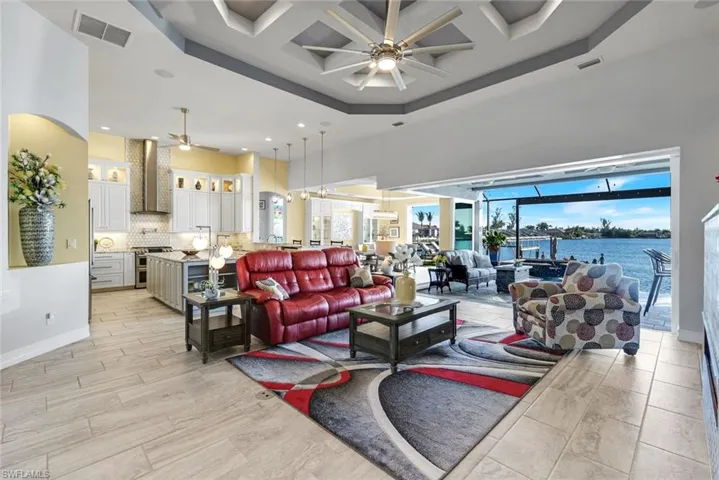 Great Room with coffered ceiling, a water view of gulf access Lavedo Lake, custom ceiling fan, recessed lighting