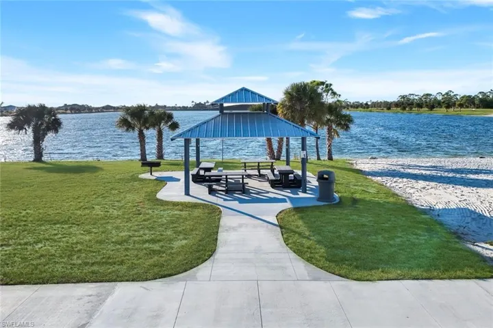 View of newly completed Crystal Lake Park w/ Beach and boat launch.  Patio areas, a lawn, and a water views