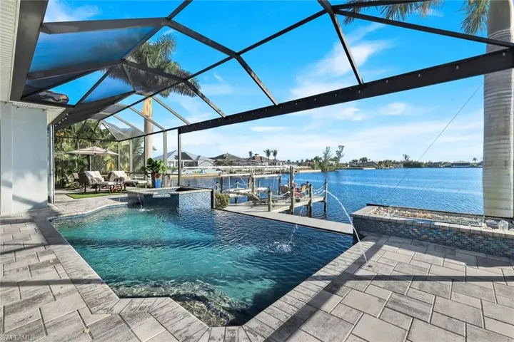 Dock area featuring 10,000 lb boat lift and composite dock, a pool with connected hot tub, a lanai, a water view of Lavedo Lake