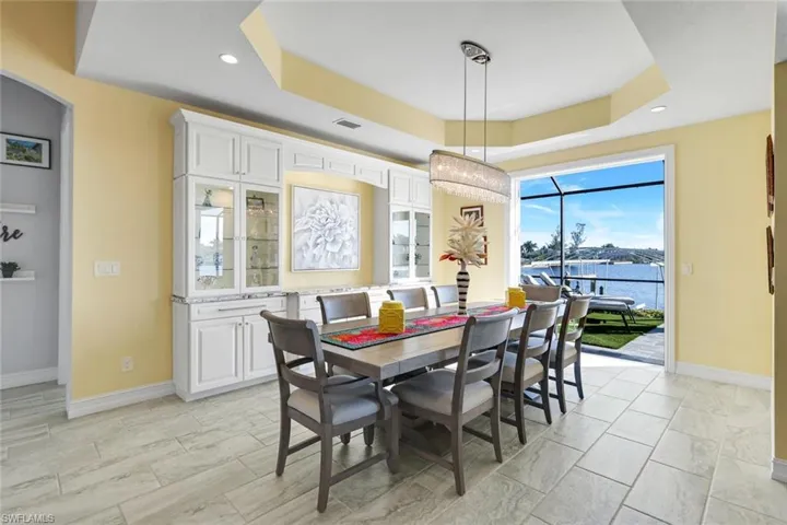 Dining area featuring a view of Lavedo Lake, tray ceiling, recessed lighting, and custom lighting