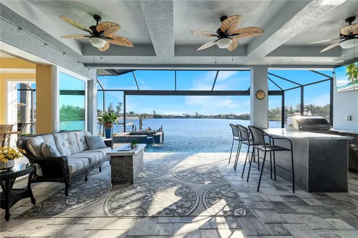 View of lanai with custom ceiling fans, outdoor kitchen and water view of Lavedo Lake