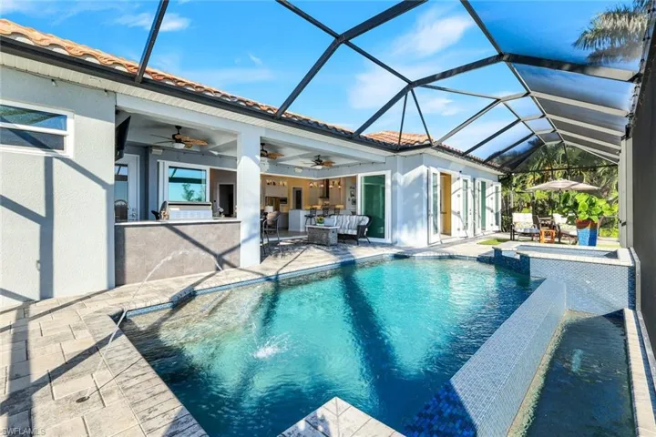 View of swimming pool with paver pool deck, a lanai, a pool with connected hot tub, and outdoor dining area