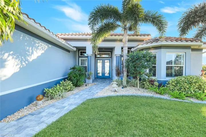 View of exterior entry with a concrete tiled roof, stucco siding, a yard, and double door impact doors