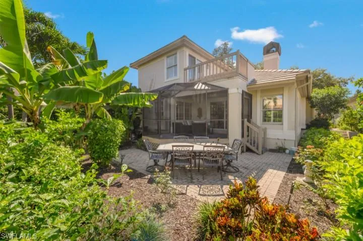 Back of property featuring a screened lanai, patio area, a serene garden and primary balcony
