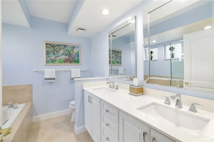 Primary bath with quartz counters and custom cabinetry