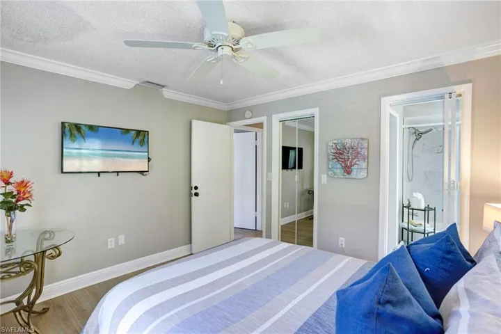 Bedroom with hardwood / wood-style flooring, ceiling fan, crown molding, and a textured ceiling