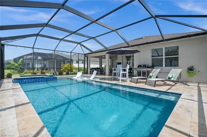 View of swimming pool featuring a patio, a pool with connected hot tub, and glass enclosure