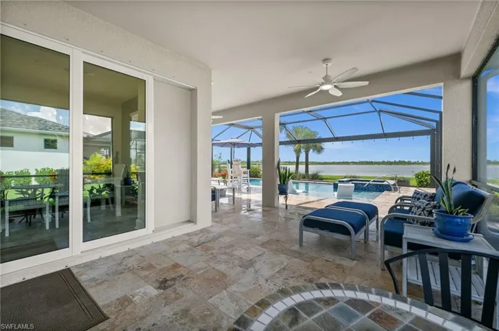 View of patio / terrace featuring an outdoor hot tub, a ceiling fan, a water view, an outdoor pool, and glass enclosure