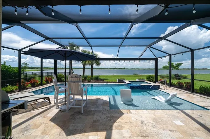View of pool with a water view, a patio area, a pool with connected hot tub, and glass enclosure