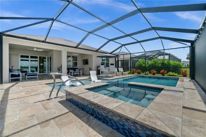 View of pool featuring a ceiling fan, a patio, a pool with connected hot tub, and a lanai
