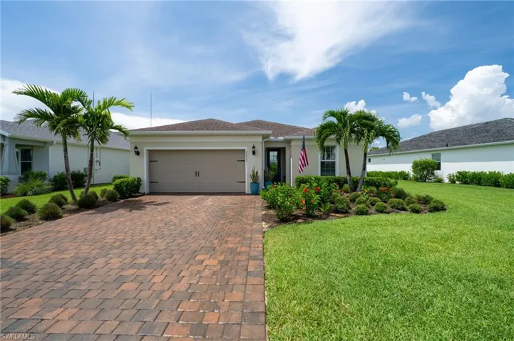 Single story home with decorative driveway, an attached garage, a front yard, and stucco siding