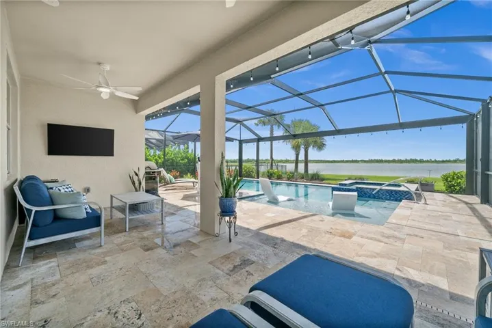View of patio with a water view, ceiling fan, a pool with connected hot tub, and a lanai