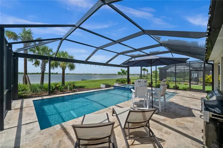 View of swimming pool featuring a water view, a patio, a pool with connected hot tub, area for grilling, and a lanai