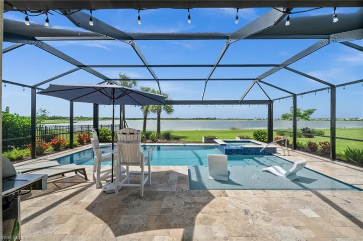View of swimming pool featuring a water view, a patio area, glass enclosure, and a pool with connected hot tub