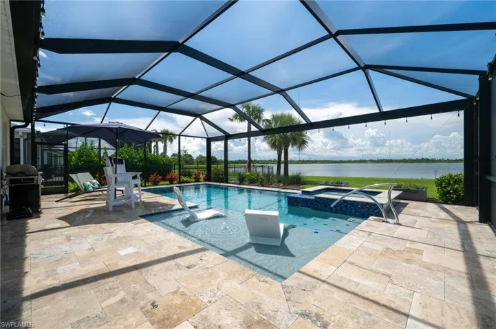 View of pool with a water view, a patio area, a pool with connected hot tub, and a grill