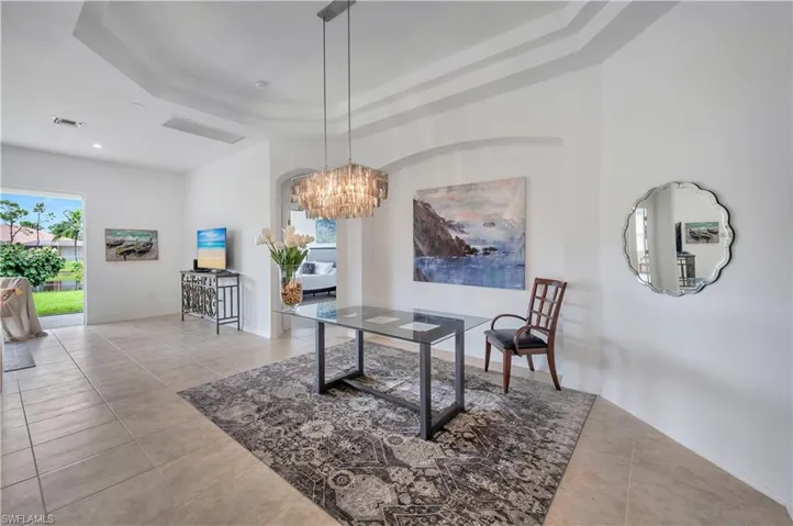 Dining area with a raised ceiling, healthy amount of natural light, a chandelier, and light tile patterned flooring