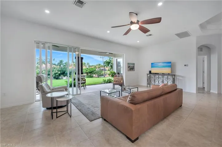 Living room featuring arched walkways, ceiling fan, recessed lighting, and light tile patterned floors