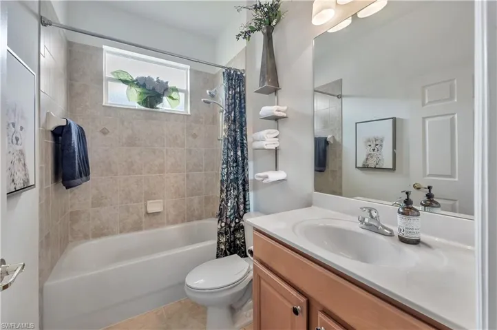 Full bath featuring shower / bath combo with shower curtain, vanity, and light tile patterned floors